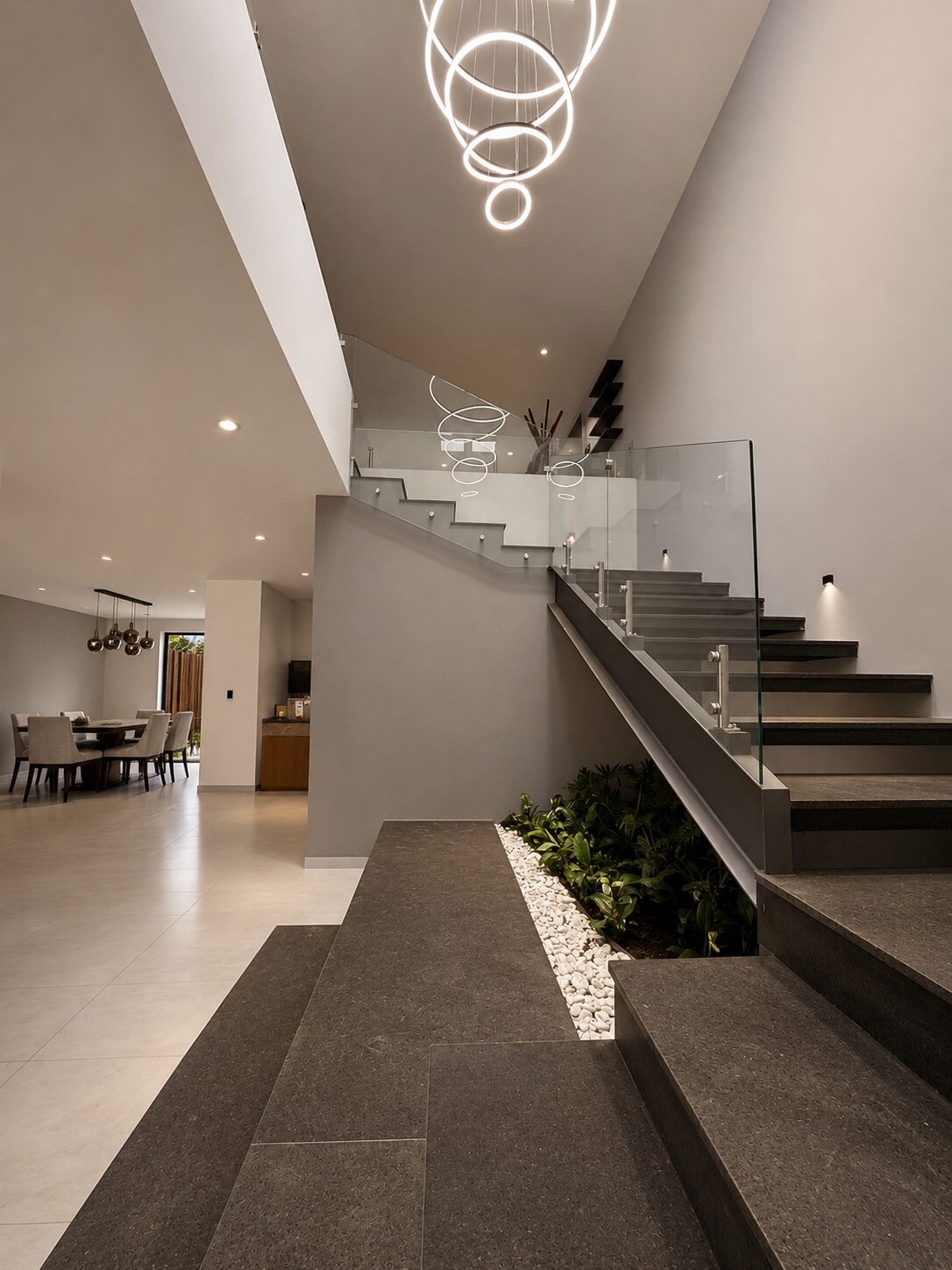 Hall de acceso a doble altura con escalera y jardinera interior · Casa Britania en Morelia