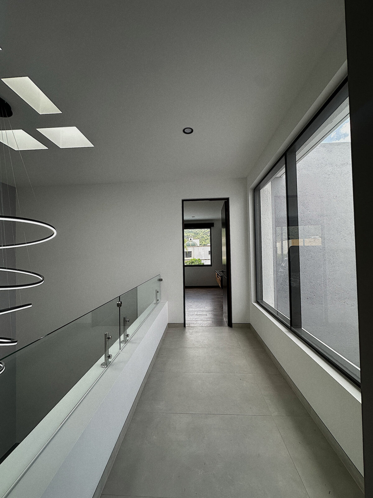 Pasillo de planta alta con barandal de cristal · Casa Britania, residencia contemporánea en Morelia